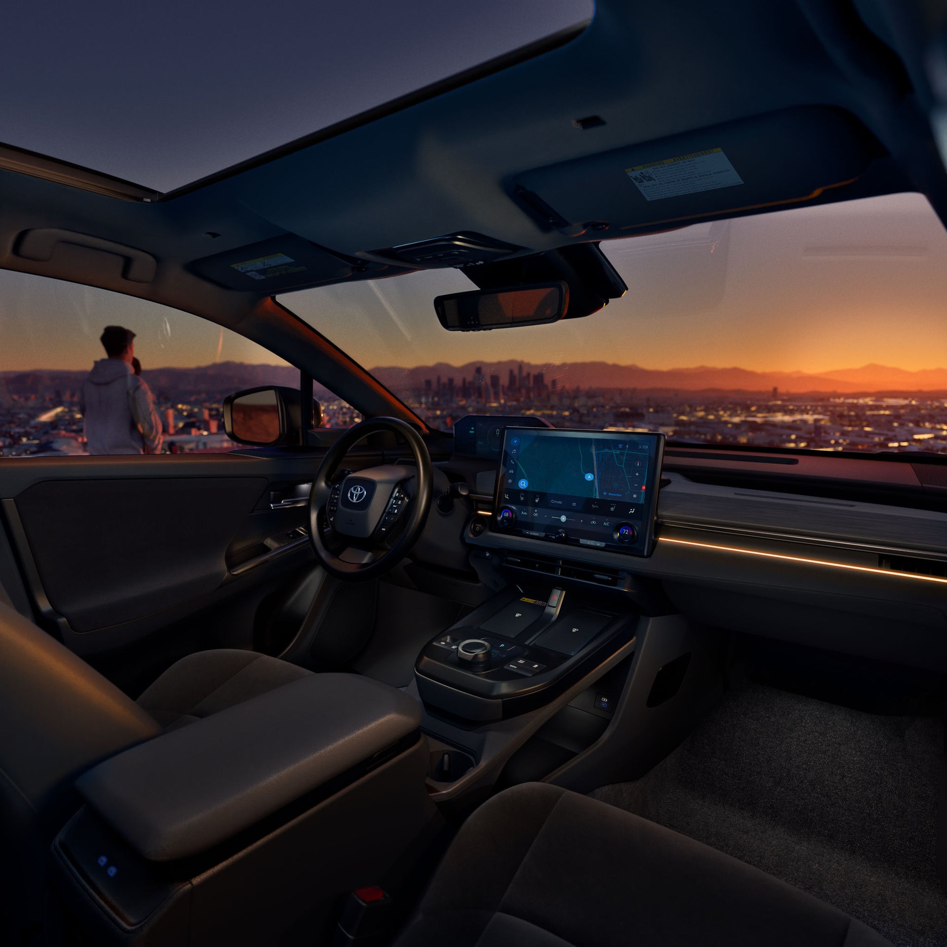 Interior of a Toyota C-HR electric SUV at dusk with a city skyline beyond the windshield