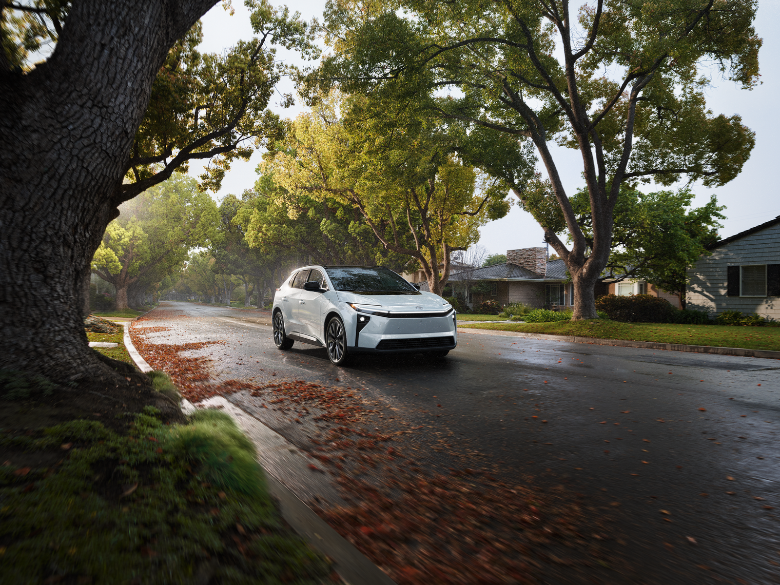 White Toyota bZ electric SUV parked on a tree-lined residential street