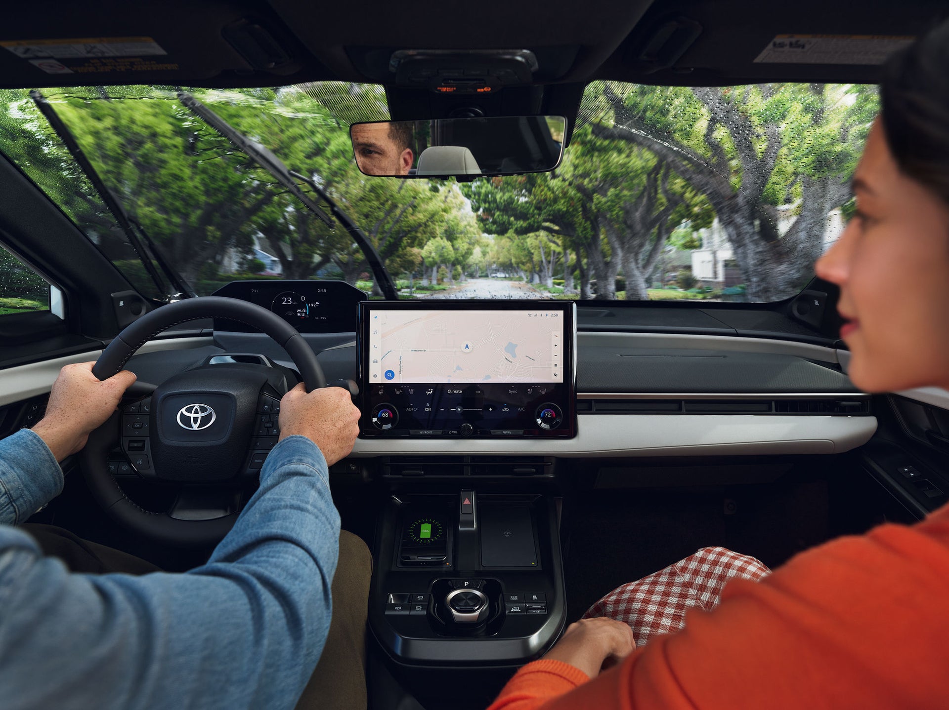 Driver and passenger inside a Toyota bZ with the center touchscreen showing navigation